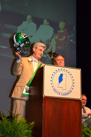 Governor Phil Bryant holds up a Delta State football helmet presented to him by Delta State President Dr. John M. Hilpert (right) during the opening ceremony of the 77th Annual Meeting of Delta Council.  Along with the helmet, Bryant was given a university pennant and baseball signed by Boston Red Sox Hall of Famer and legendary Delta State baseball coach Dave “Boo” Ferriss.